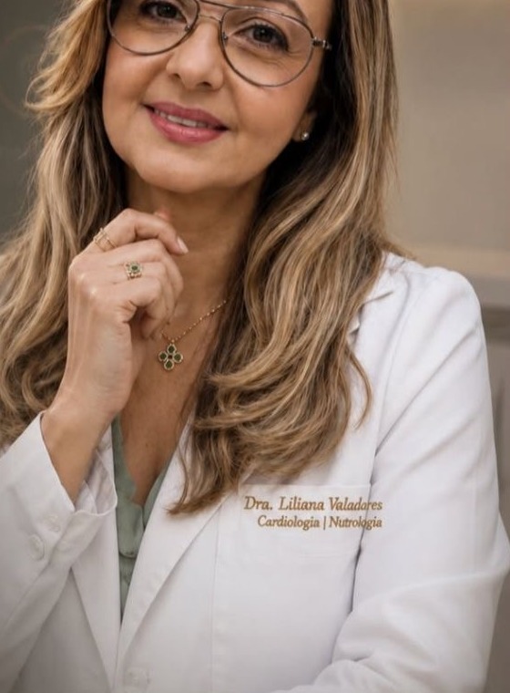 Dra. Liliana Valadares, médica cardiologista e nutróloga, sorrindo de jaleco branco em consultório
